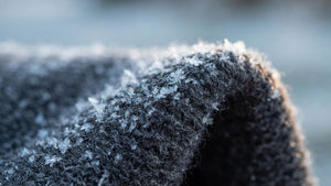 Close-up of a charcoal grey merino wool knit covered in frost crystals